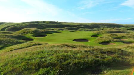 Links golf green surrounded by deep bunkers and grassy dunes