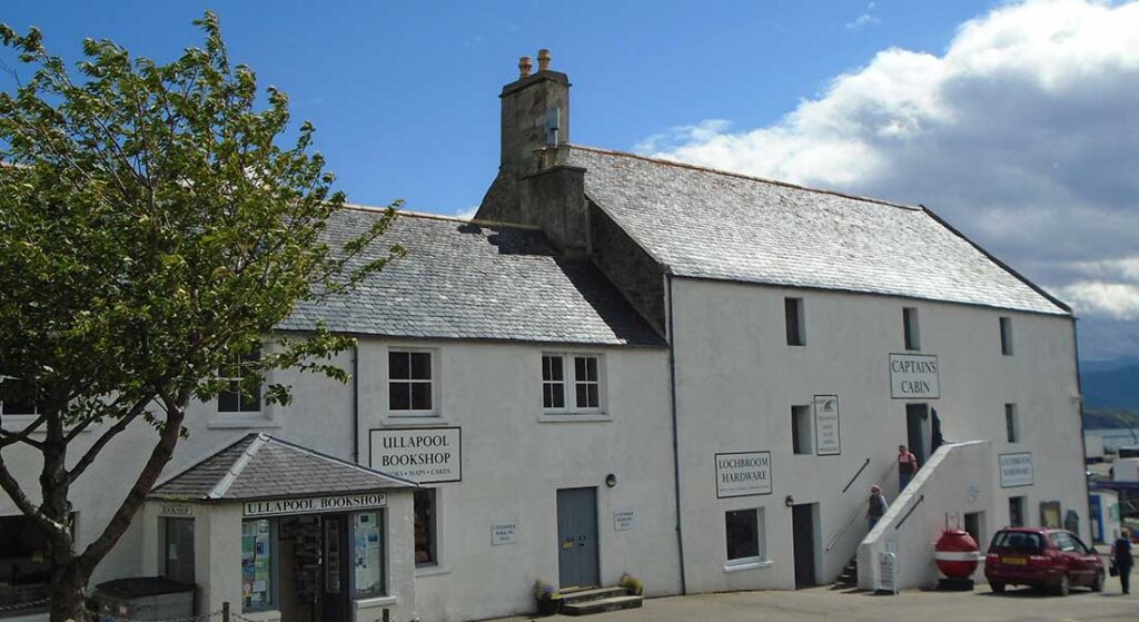 Whitewashed buildings housing Ullapool Bookshop and Captains Cabin under grey slate roofs