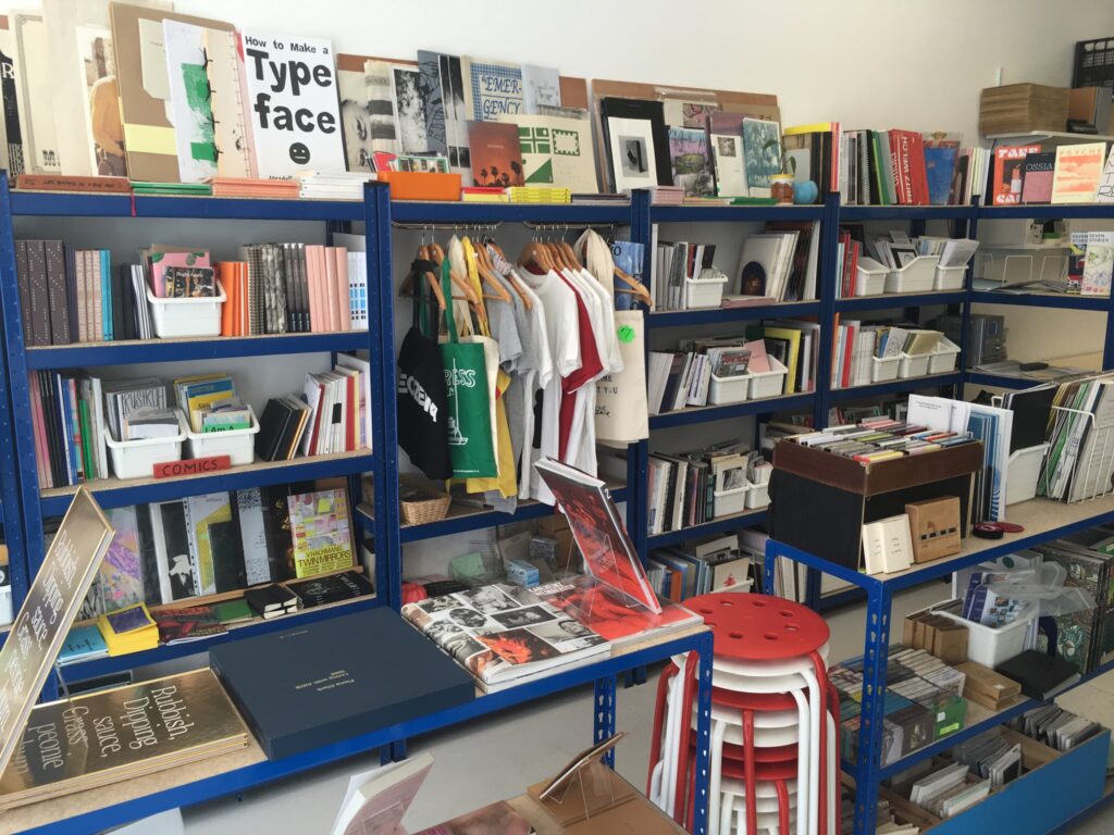 Blue metal shelves of books, zines and prints.