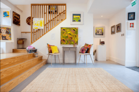 Paintings and chairs in the bright white rooms of the gallery.