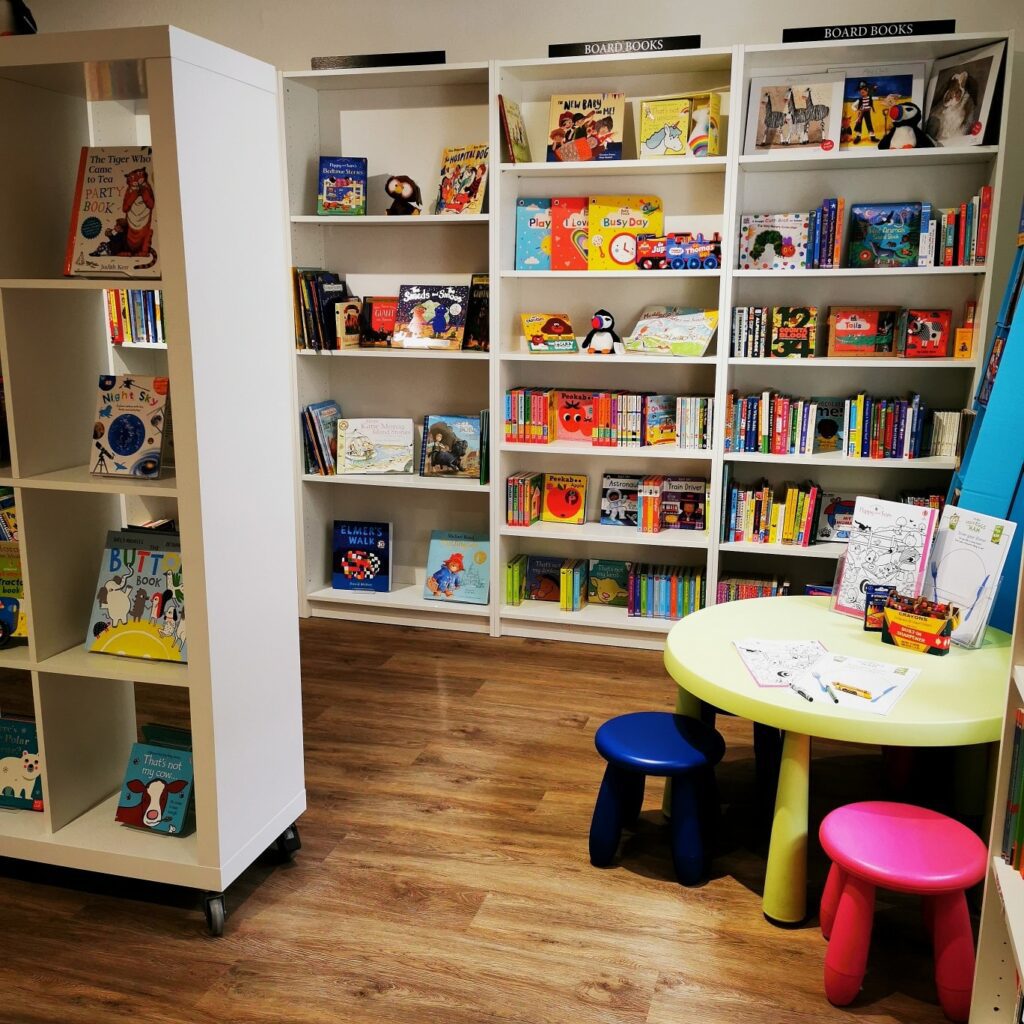 The children's corner of the Orcadian Bookshop, shelves of picture books above small chairs and a table.