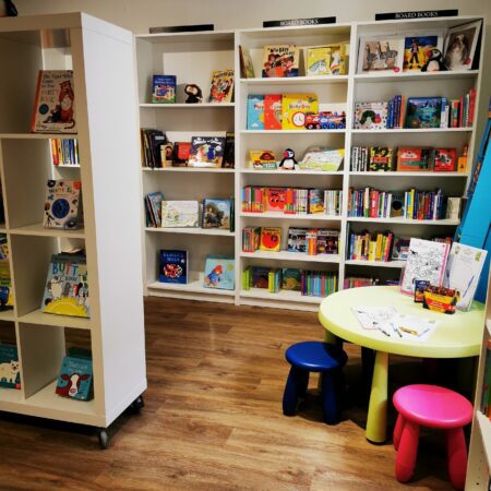 The children's corner of the Orcadian Bookshop, shelves of picture books above small chairs and a table.