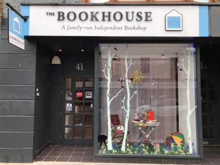 The Bookhouse's grey shopfront, its window dressed with birch trees.