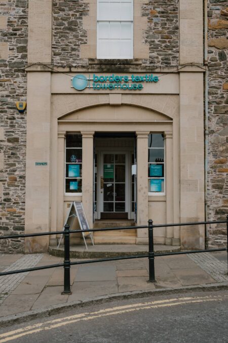 Stone entrance to Borders Textile Towerhouse with arched doorway and sandwich board