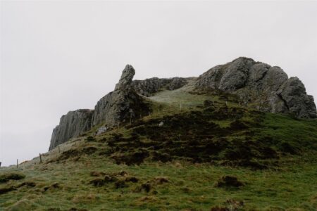 Rocky outcrop with jagged pinnacle rising above a grassy hillside