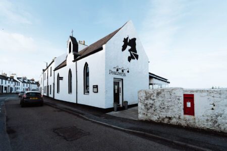Peatzeria's whitewashed building on Shore Street, Bowmore, with its belfry and pointed windows.