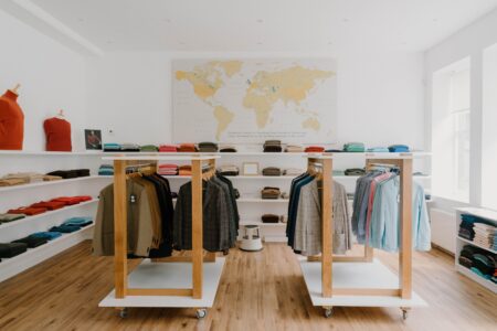 Clothing shop interior with wooden rails, folded jumpers on shelves and a world map