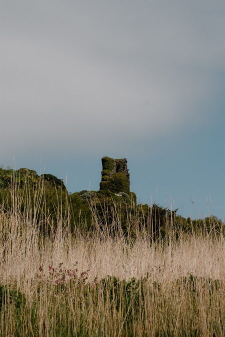 Ruined stone tower on a hillside beyond tall dune grasses