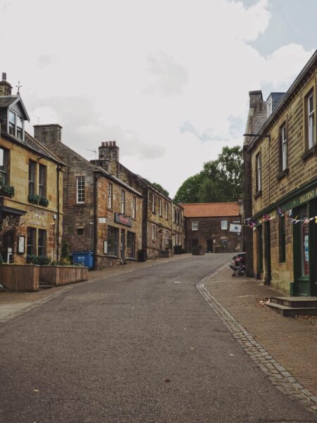 Sandstone cottages and shopfronts line a quiet curving street with bunting overhead