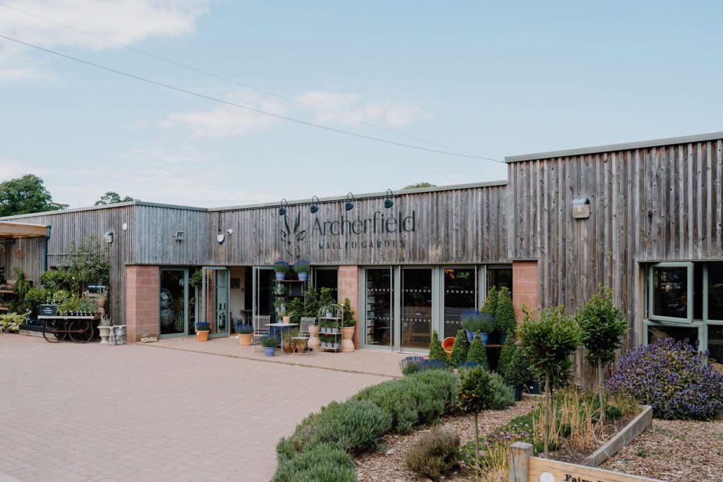 Timber-clad Archerfield Walled Garden building with plants displayed outside the entrance