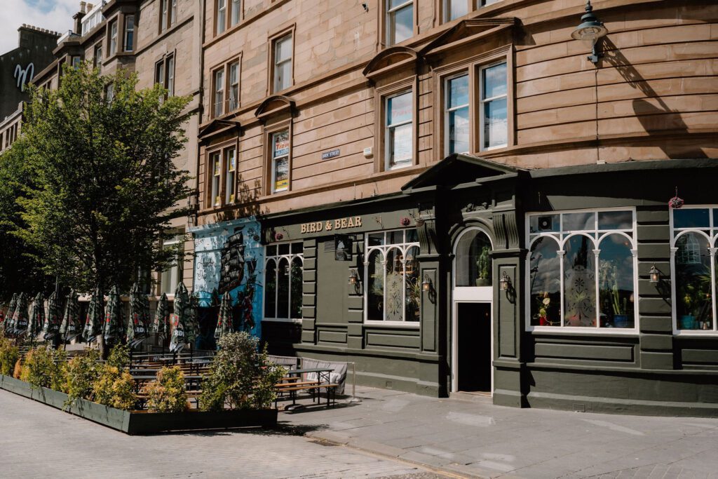 Sandstone tenement building with green-fronted corner pub below