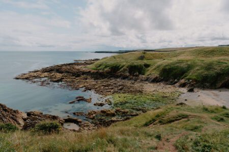 Grassy headland overlooking a rocky shoreline and calm coastal waters