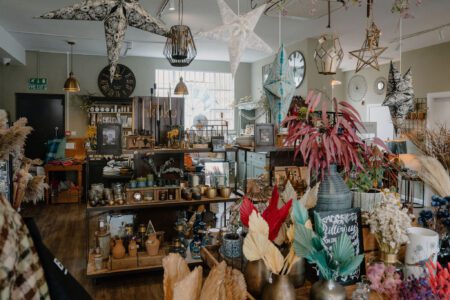 Star-shaped lanterns hang above shelves of dried flowers, clocks and ornaments in a gift shop