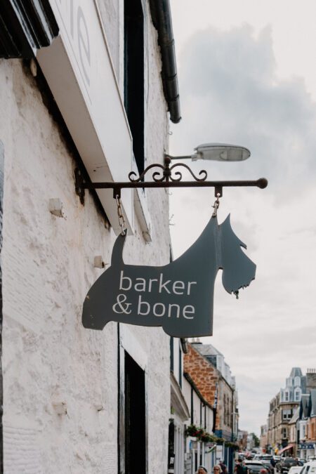 Terrier-shaped "Barker & Bone" sign hanging from a whitewashed shopfront