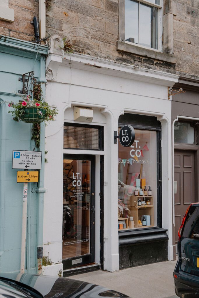 Laura Thomas Co shopfront with hanging basket and parking sign on street corner