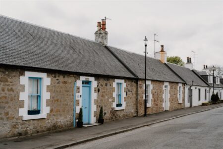 Single-storey stone cottages with white-trimmed windows and a pale blue door