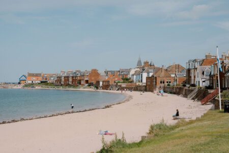 Sandy beach curves beneath a row of coastal houses and a church spire