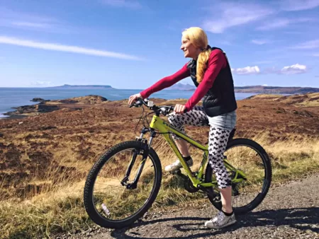 Woman on a mountain bike pauses on a coastal path overlooking the sea