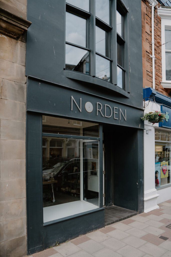Dark-fronted Norden shopfront with sash windows on a sandstone terrace
