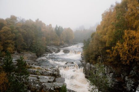 River tumbling over rocky falls through a mist-covered autumn woodland