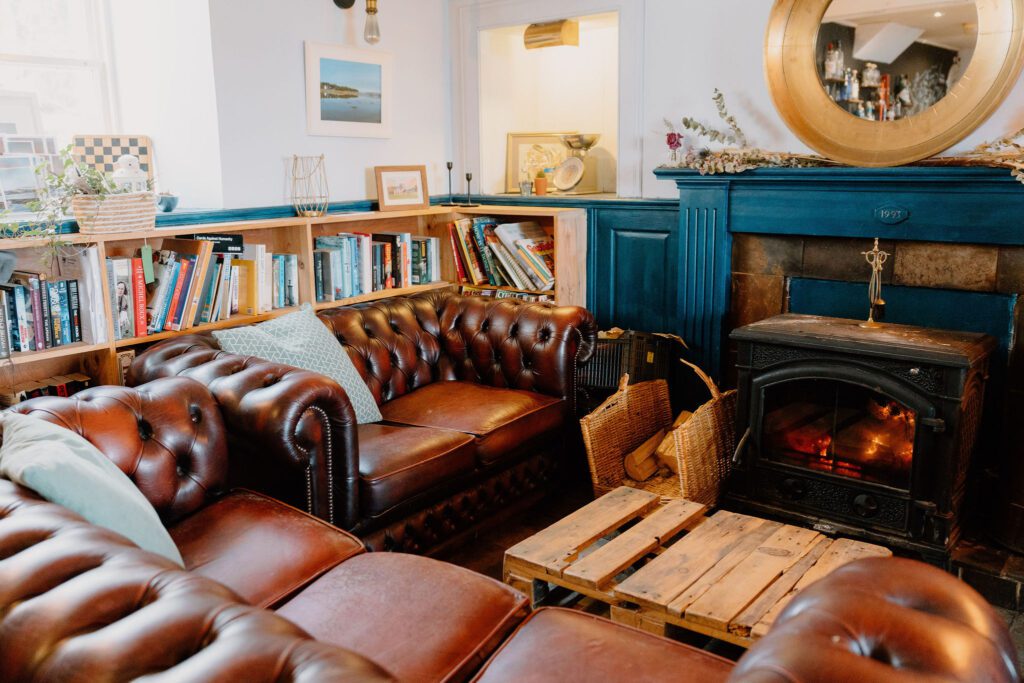 Leather sofas round a lit stove and shelves of books in the Oystercatcher.