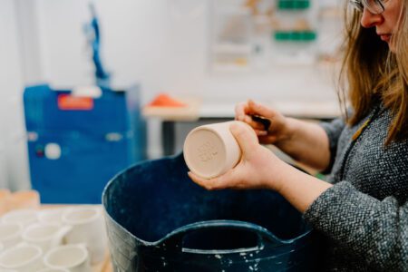 Potter carves a maker's mark into the base of a clay mug