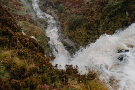 Waterfall cascading through rocky gorge lined with autumn heather and ferns