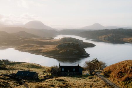 Stone cottage overlooking a sea loch with distant hills at sunrise