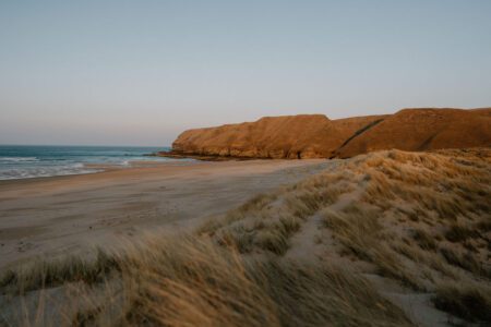 Sandy beach and dune grass beneath cliffs at dusk