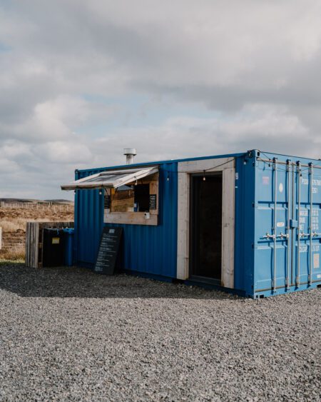 Blue shipping container converted into a food kiosk with serving hatch open