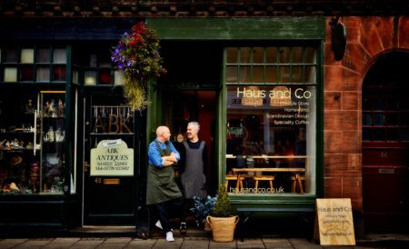 Two aproned men chat outside Haus and Co, next to ABK Antiques
