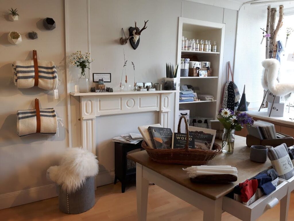 Shop interior with striped bags, sheepskin stool and books on a mantelpiece display