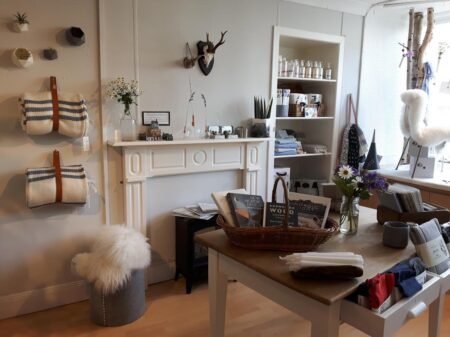 Shop interior with striped bags, sheepskin stool and books on a mantelpiece display