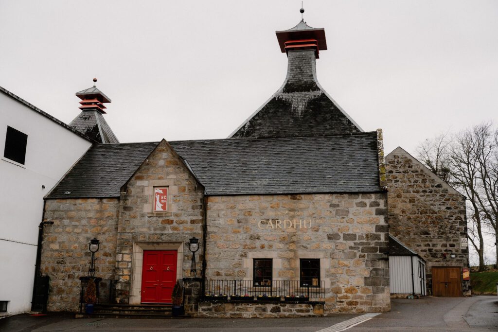 Cardhu distillery building with pagoda roofs and red door under grey sky