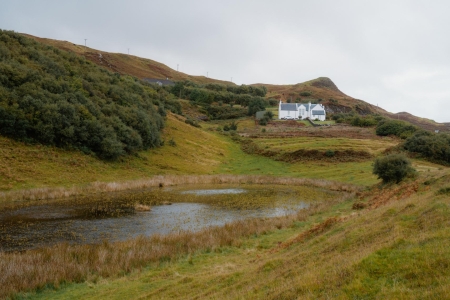White cottages on a hillside above a small loch