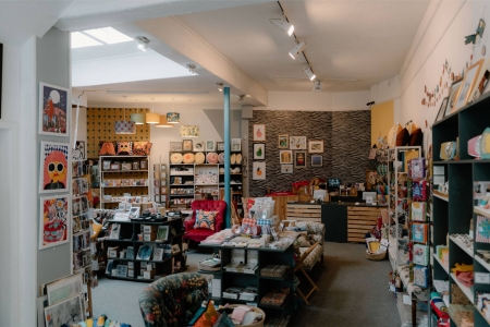Gift shop interior with framed prints, greetings cards and a red armchair