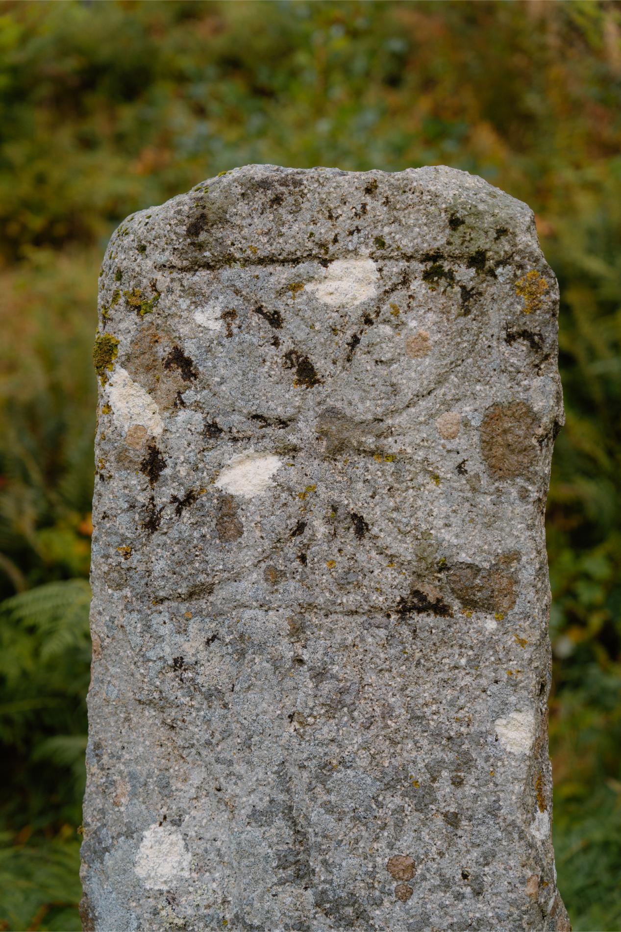 Weathered granite stone marker with a faint carved cross design