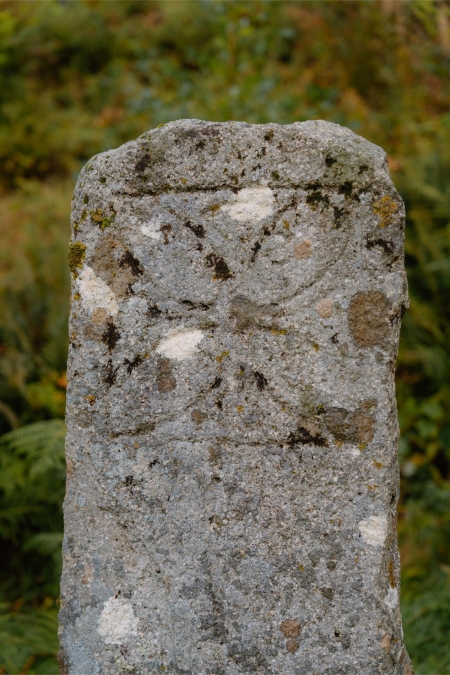 Weathered granite stone marker with a faint carved cross design