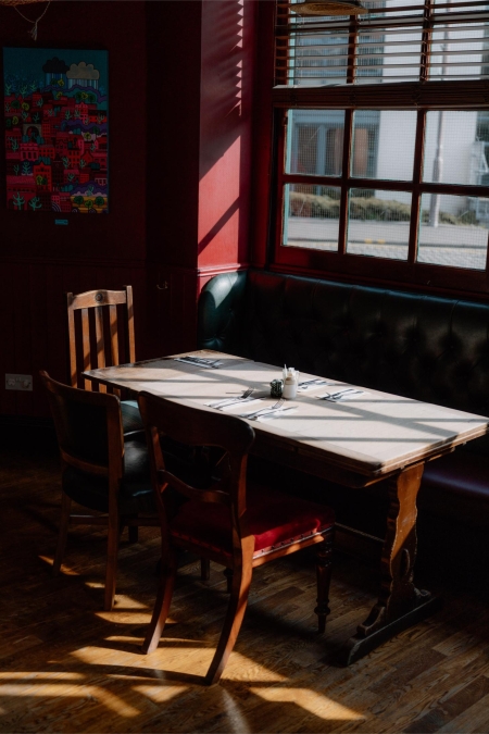 Sunlit table set for two beside a leather booth and window
