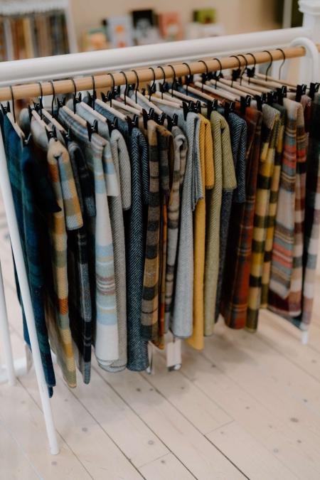 Tartan and check wool scarves hang on a white shop rail
