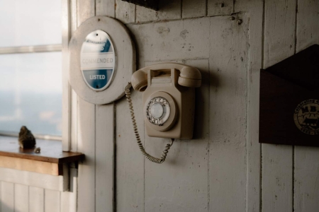 Cream rotary telephone mounted beside a round "Listed" plaque on wooden panelling