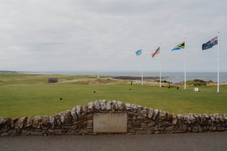 Flags fly above Balcomie golf course, coastline stretching towards the sea