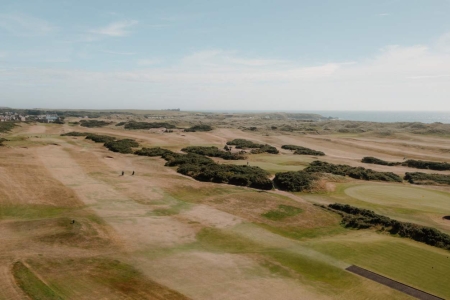Aerial view of a coastal links golf course with rolling fairways and dunes