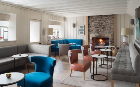 Lounge with blue and coral armchairs around a stone fireplace