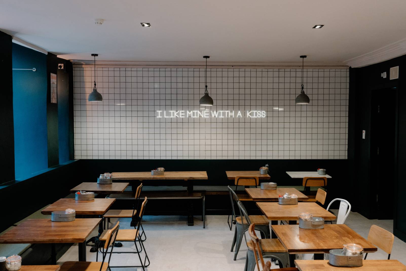 Neon sign reading "I like mine with a kiss" above café tables