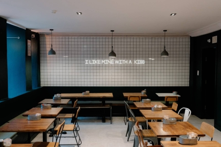 Neon sign reading "I like mine with a kiss" above café tables