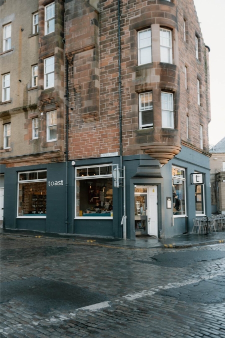 Sandstone tenement building on a corner, with Toast shopfront below