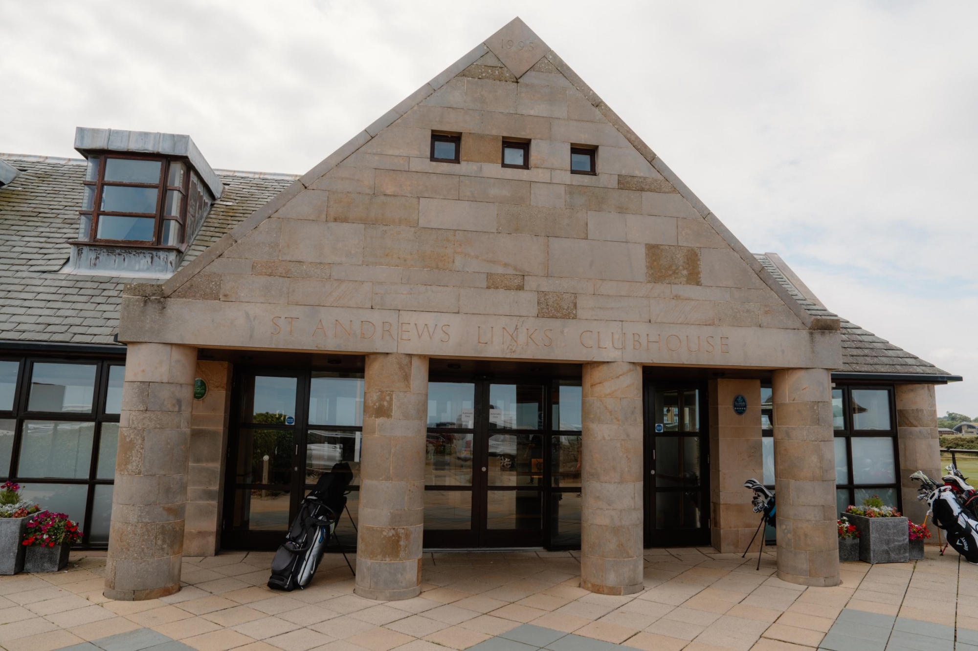 Stone gable of St Andrews Links Clubhouse, golf bags resting by the entrance