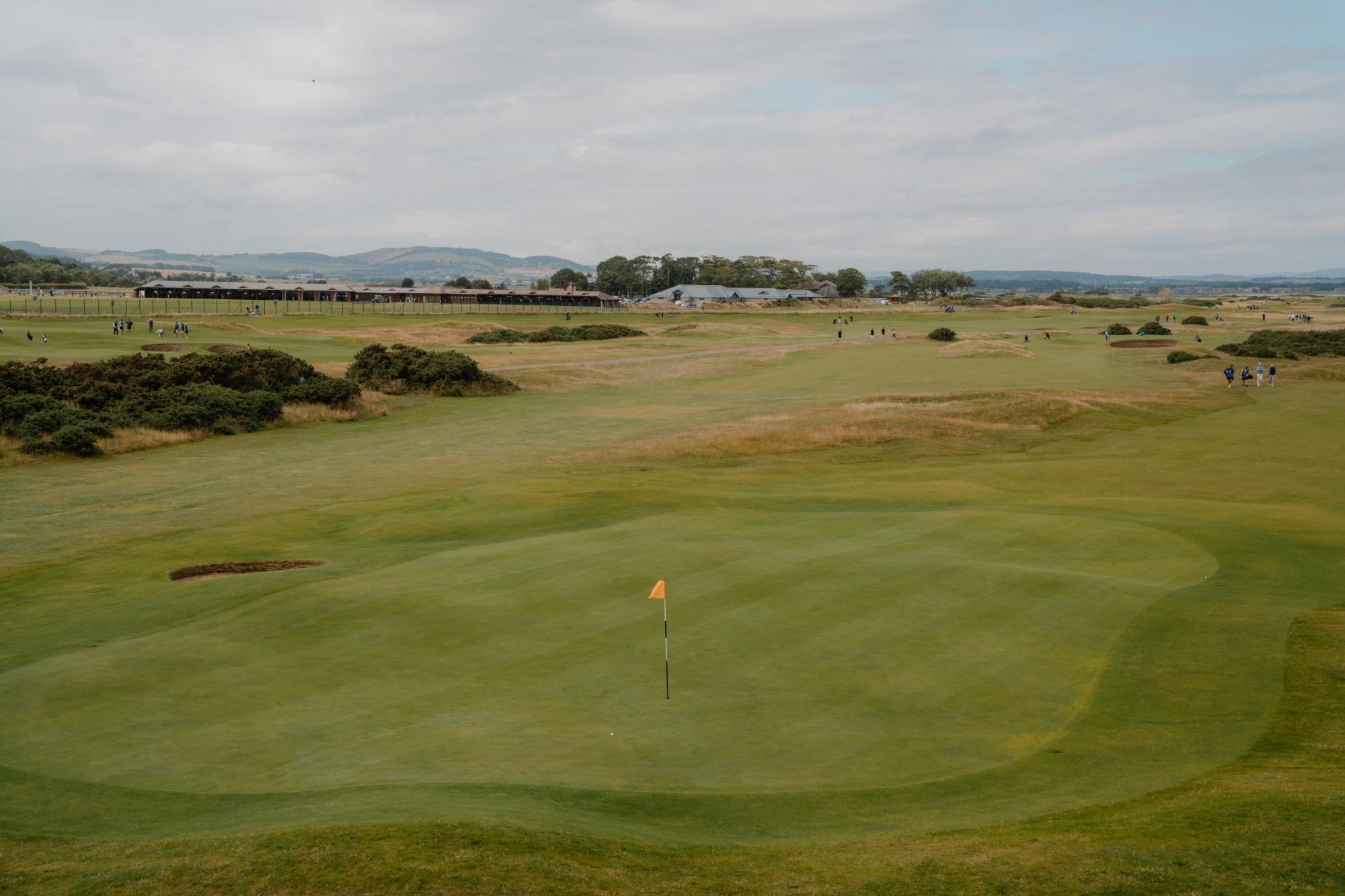 Yellow flag on a links golf green with distant hills