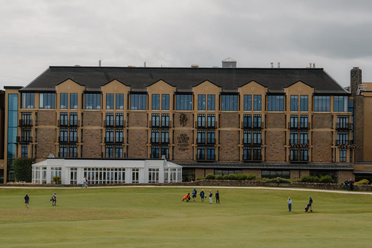 Golfers cross a fairway before the Old Course Hotel's gabled facade